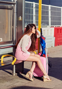 Woman sitting at bus stop in city