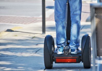 Low section of man riding on segway at sidewalk