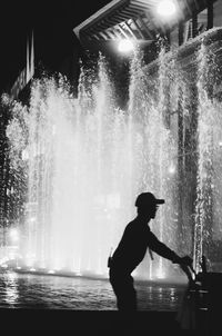 Silhouette man standing by fountain at night