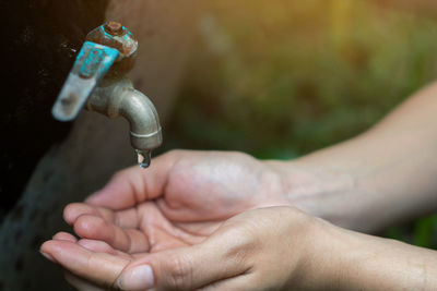 Close-up of human hand below faucet