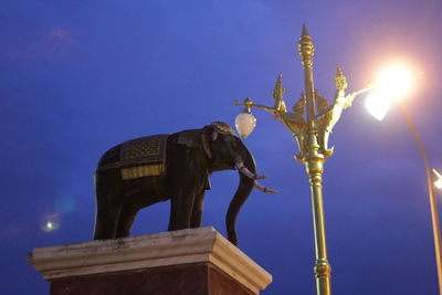 Low angle view of statue against illuminated city