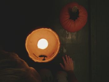 Low section of person holding illuminated pumpkin