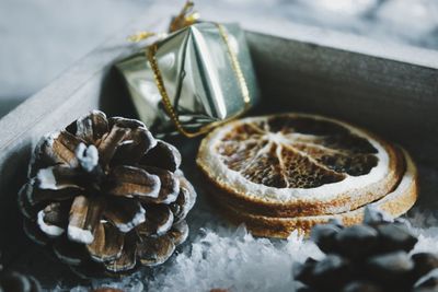 Close-up of pine cones with dry orange slices with christmas present in box