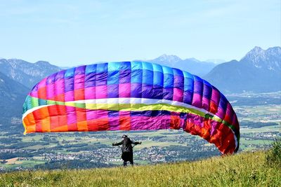 Rear view of man paragliding against landscape