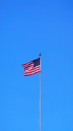 Low angle view of american flag against clear blue sky