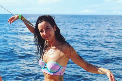 Portrait of smiling woman wearing bikini against sea