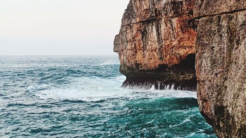 Rock formation in sea against clear sky