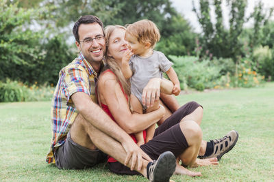 Happy friends sitting on grass in park