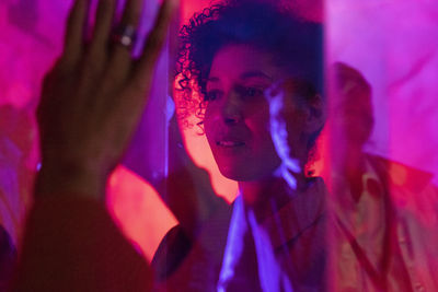 Female entrepreneur examining glass display during corporate event at illuminated workshop