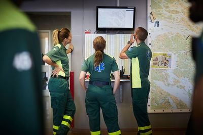 Male and female paramedics discussing while looking at screen in hospital