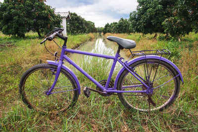 Bicycle parked on field against sky