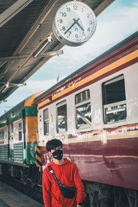 Man standing by train at railroad station