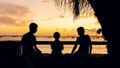 Silhouette people at beach during sunset