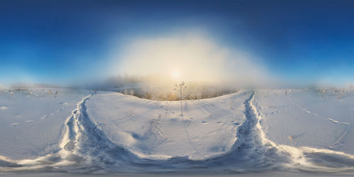 Snow covered land against clear blue sky