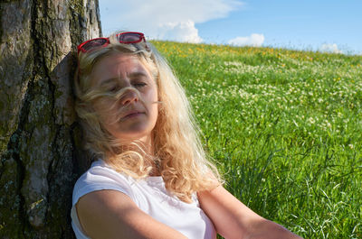 Woman leaning against a tree, meditating and enjoying a moment of nature calmness in springtime