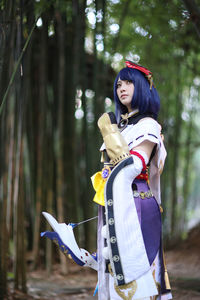 Side view of woman wearing hat standing in forest