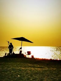 Silhouette people standing on beach against clear sky during sunset