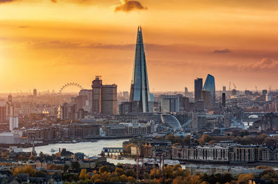 Modern buildings in city against sky during sunset