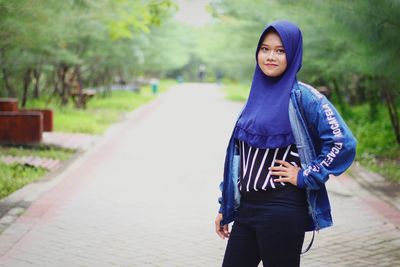 Portrait of young woman standing on footpath