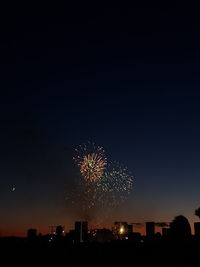 Firework display in city against sky at night