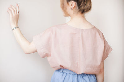 Rear view of mid adult woman standing by white walls