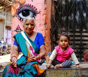 Portrait of cute granddaughter sitting with grandmother