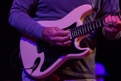 Midsection of man playing guitar