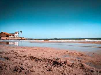 Scenic view of beach against clear blue sky