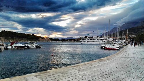 Boats in calm sea against cloudy sky