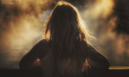 Rear view of woman with blond hair standing by railing