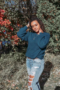 Portrait of beautiful young woman standing against tree