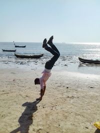 Side view of man exercising on sand at beach