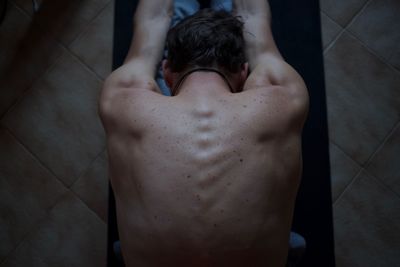 Directly above shot of shirtless man stretching at home