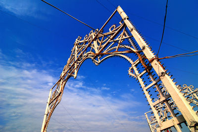 Low angle view of electricity pylon against blue sky