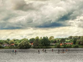 People playing on beach against sky