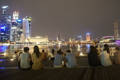 Rear view of people looking at city at night