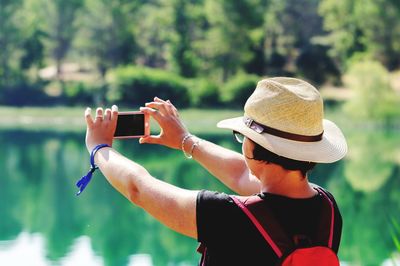 Rear view of woman photographing lake