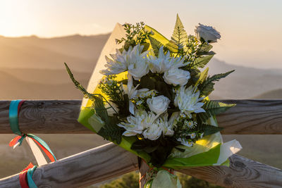 Memorial buquet flowers tied on a wooden fence, outdoors.