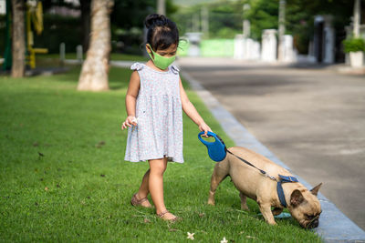 Little girl with protective face mask to prevent virus and pm2.5 walk the dog at field.