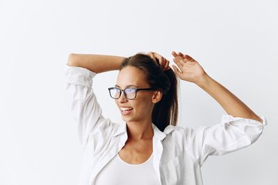 Portrait of young woman with arms crossed against white background