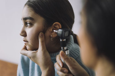 Doctor doing hearing test of female patient through otoscope at hospital