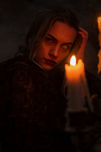 Portrait of young woman holding lit candle