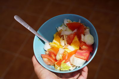 Close-up of hand holding fruit salad in bowl