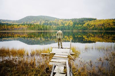 Full length of man standing on pier by lake against sky