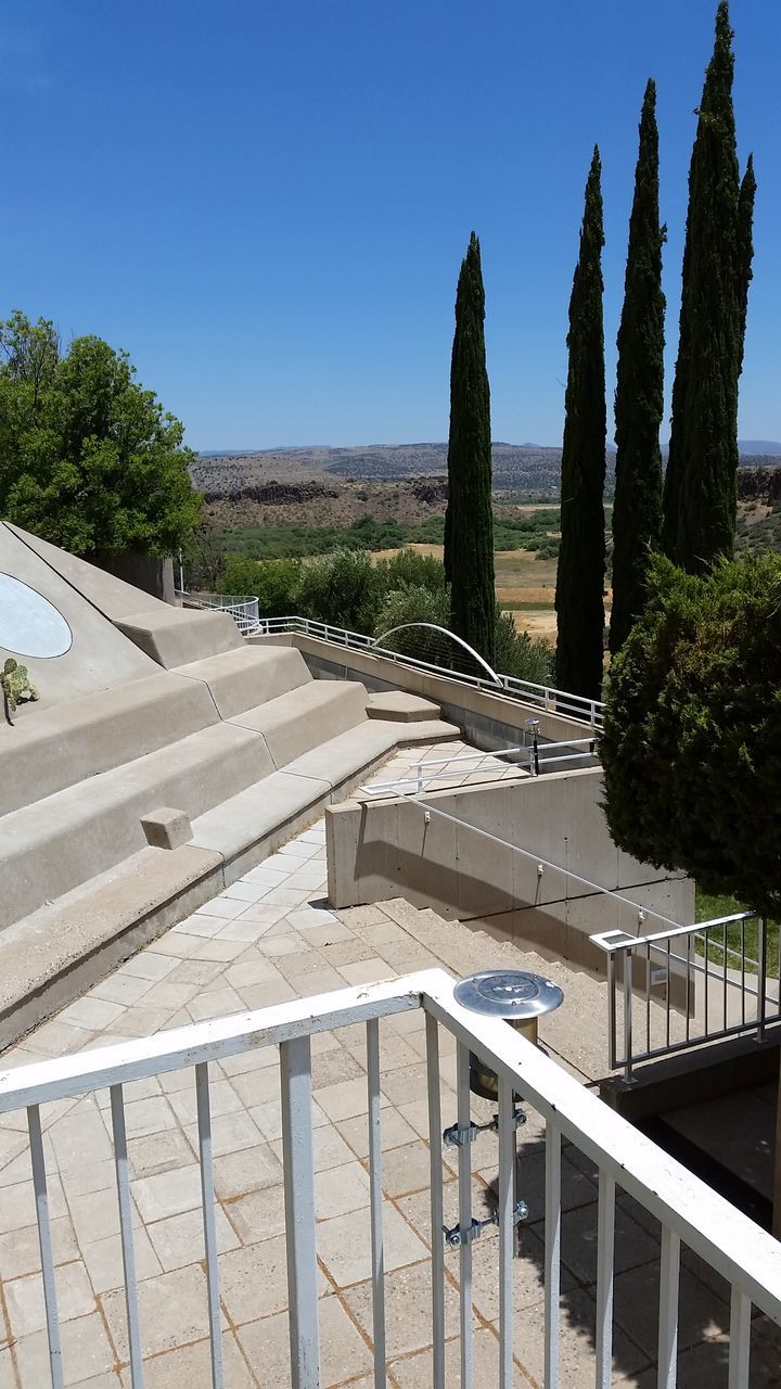 railing, clear sky, day, tree, sunlight, steps and staircases, no people, outdoors, nature, sky, terrace, built structure, water, architecture