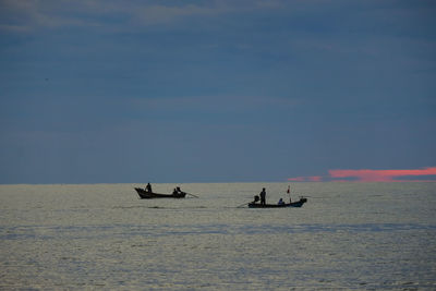 People sailing in sea against sky