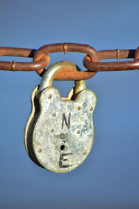 Close-up of padlocks on rusty chain against blue sky