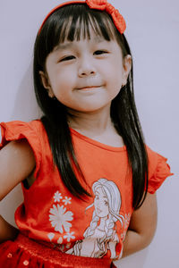 Portrait of cute girl against red wall