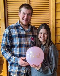 Portrait of smiling man with pregnant wife and balloon at home
