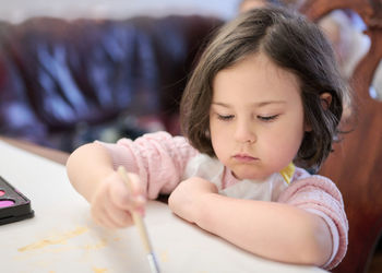 Concentrated girl is painting with watercolors